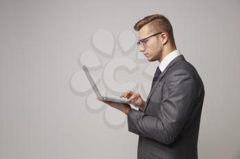 Studio Portrait Of Businessman Using Laptop