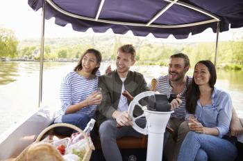 Group Of Friends Enjoying Day Out In Boat On River Together