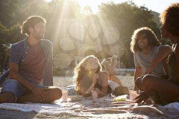 Four friends having a picnic on the beach, lens flare, Ibiza