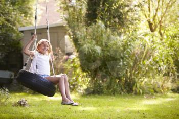 Portrait Of Young Girl Playing On Tire Swing In Garden