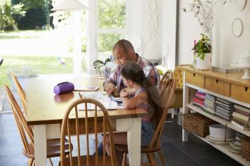 Father Helping Daughter With Homework At Table