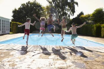 Rear View Of Children Jumping Into Outdoor Swimming Pool