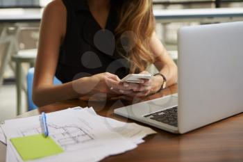 Businesswoman working in office using phone, mid section