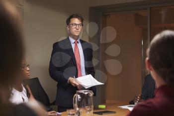 Young white businessman addresses team at meeting, low angle