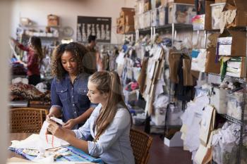 Woman training apprentice at clothes manufacturing workshop