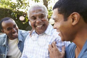 Senior man talking with his adult sons in garden, close up