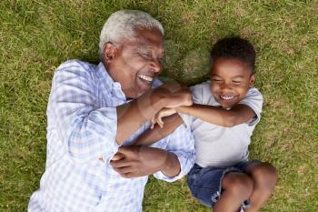 Grandfather and grandson play lying on grass, aerial view