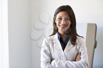 Portrait Of Female Doctor Wearing White Coat In Exam Room