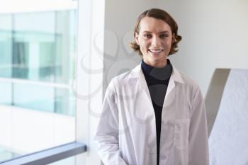 Portrait Of Female Doctor Wearing White Coat In Exam Room