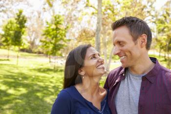 Happy mixed race couple in park looking at each other