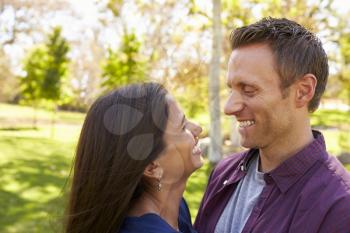 Happy mixed race couple in park look at each other, close up