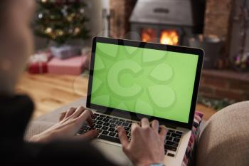 Man Using Laptop In Room Decorated For Christmas