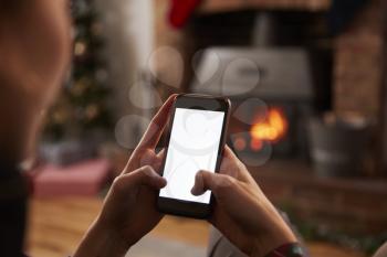 Man Using Mobile Phone In Room Decorated For Christmas