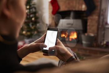 Man Using Mobile Phone In Room Decorated For Christmas