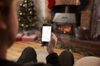 Man Using Mobile Phone In Room Decorated For Christmas