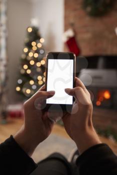 Man Using Mobile Phone In Room Decorated For Christmas