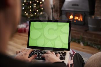 Man Using Laptop In Room Decorated For Christmas