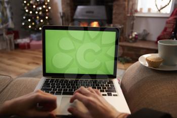 Man Using Laptop In Room Decorated For Christmas