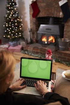 Woman Using Laptop In Room Decorated For Christmas