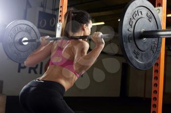 Rear View Of Woman In Gym Lifting Weights On Barbell