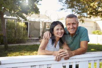 Portrait Of Mature Couple Looking Over Back Yard Fence