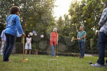 Group Of Mature Friends Playing Croquet In Backyard Together