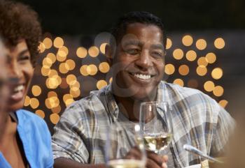 Group Of Mature Friends Enjoying Outdoor Meal In Backyard