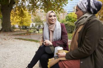 Two British Muslim Women Eating Lunch In Park Together