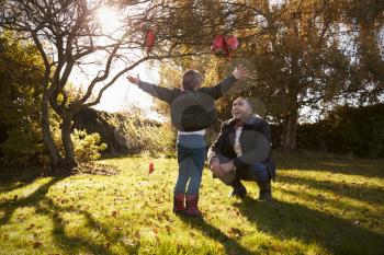 Boy And Father Playing With Autumn Leaves in Garden