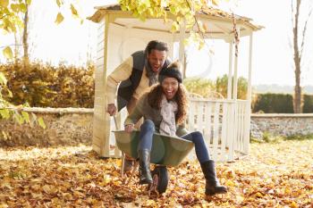 Man In Autumn Garden Gives Woman Ride In Wheelbarrow