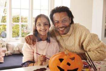 Father And Daughter Making Halloween Decorations At Home