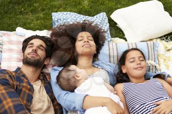 Overhead View Of Family Relaxing On Rug In Garden Together