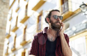 Bearded young man in sunglasses using phone, Ibiza, Spain