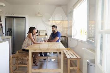 Adult couple talk and drink wine in the kitchen, full length