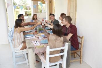 Friends making a toast at a dinner party on a patio, Ibiza