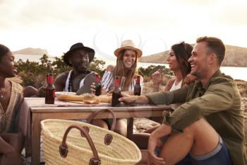 Group Of Friends Enjoying Picnic On Cliffs By Sea