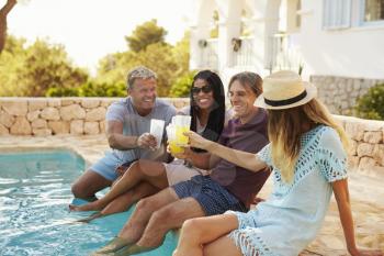 Two couples make a toast with legs dipping in swimming pool