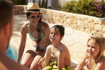 Family On Vacation Relaxing By Outdoor Pool