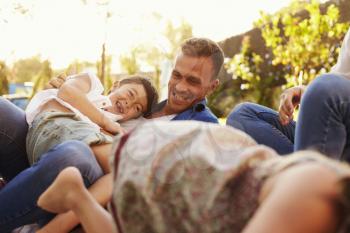 Parents Playing Game With Children On Blanket In Garden