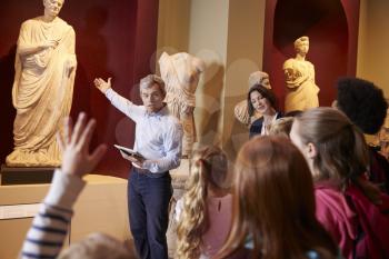 Pupils And Teacher On School Field Trip To Museum With Guide