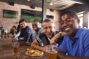Portrait Of Male Friends At Counter In Sports Bar