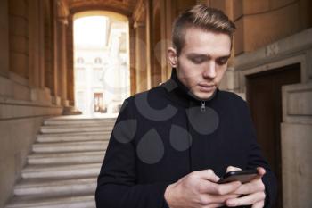 Man Checking Messages On Mobile Phone In Urban Setting