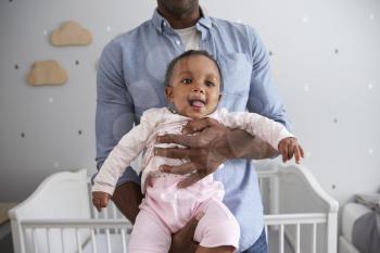 Close Up Of Father Holding Baby Daughter In Nursery