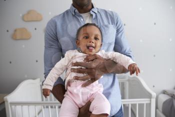 Close Up Of Father Holding Baby Daughter In Nursery