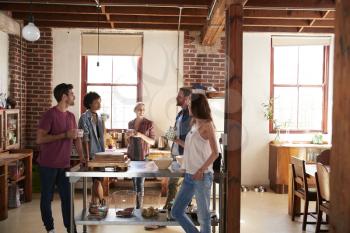 Friends talking over coffee in kitchen, three quarter length