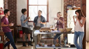 Five friends stand hanging out in kitchen, quarter length