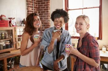 Three girlfriends in kitchen look to camera, close up