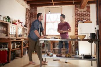 Two male friends hanging out in kitchen, full length