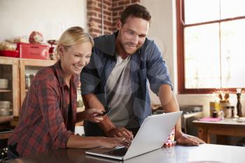 Young white couple on-line shopping in kitchen, close up