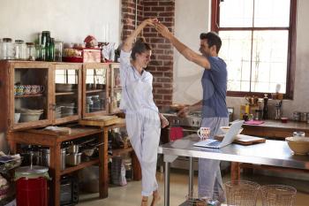 Happy Hispanic couple dancing in kitchen in the morning
